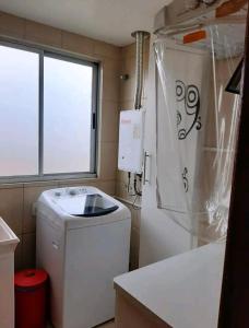 a small bathroom with a washing machine and a window at Apê aconchegante e quentinho em São Joaquim in São Joaquim