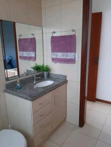 a bathroom with a sink and a toilet and a mirror at Apê aconchegante e quentinho em São Joaquim in São Joaquim
