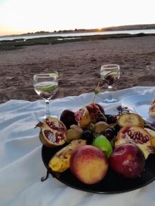 a plate of fruit on a table with two wine glasses at Araucaria in Oualidia