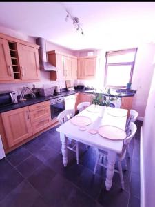 a kitchen with a white table and chairs in it at Glan-Yr-afon cottage two bedrooms in Sennybridge