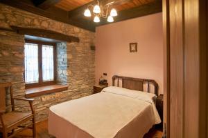 a bedroom with a bed and a chair and a window at Casa Gelito in Espinareda de Vega