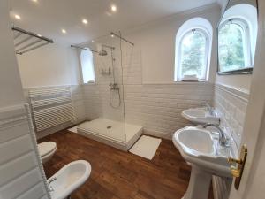 a white bathroom with two sinks and a shower at Lesní Hotel Peršlák in Nová Bystřice