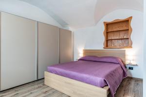 een slaapkamer met een paars bed en een kast bij Residenza Glicine in Pergine Valsugana