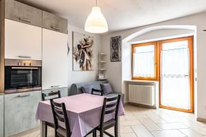 een keuken en eetkamer met een roze tafel en stoelen bij Residenza Glicine in Pergine Valsugana