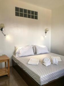 Una cama con almohadas blancas y toallas. en E.I. SUITES en Siquijor