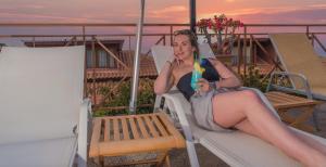 a woman in a dress sitting on a bench with a drink at Sea View Village in Vasilikos