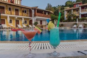 two cocktails sitting on a table next to a pool at Sea View Village in Vasilikos