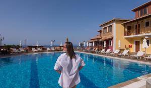 a woman standing in front of a swimming pool at Sea View Village in Vasilikos