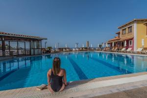 a woman sitting in front of a swimming pool at Sea View Village in Vasilikos