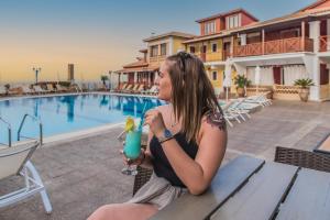 a woman sitting on a bench with a drink at Sea View Village in Vasilikos