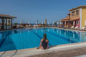 a woman sitting next to a swimming pool at Sea View Village in Vasilikos