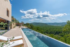 uma piscina de beiral infinito numa villa com vista para as montanhas em Villa Terra Motovun em Motovun