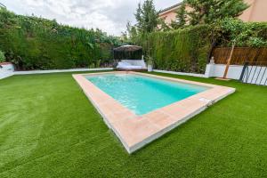 a swimming pool in a yard with a green lawn at Chalet con piscina en entorno idílico in La Zubia