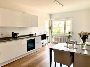 a kitchen with white cabinets and a dining table at Live Lugano - Via Madonetta in Lugano