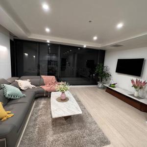 ein Wohnzimmer mit einem Sofa und einem TV in der Unterkunft Carlton Stunning View Apartment 150m away from University of Melbourne in Melbourne