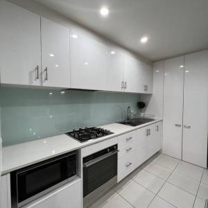 a kitchen with white cabinets and a stove top oven at Carlton Stunning View Apartment 150m away from University of Melbourne in Melbourne