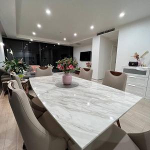 a large marble table with chairs and a vase of flowers at Carlton Stunning View Apartment 150m away from University of Melbourne in Melbourne