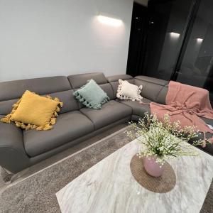 a gray couch with pillows in a living room at Carlton Stunning View Apartment 150m away from University of Melbourne in Melbourne