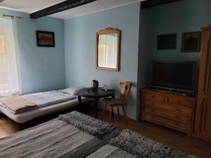 1 dormitorio con 2 camas, TV y mesa en Zachęta, en Sokolec