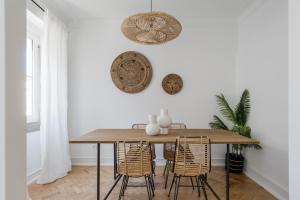 uma sala de jantar com uma mesa de madeira e cadeiras de vime em Casa Boma Lisboa - Charming and Spacious Apartment - Campolide II em Lisboa