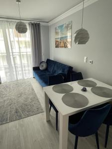 a living room with a table and a blue couch at Apartament Jantar Osiedle Bursztynowe Jantar PROMOCJA in Jantar