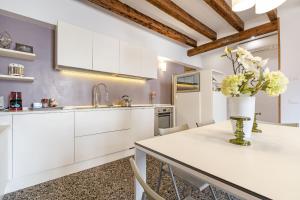 a kitchen with white cabinets and a table with flowers on it at CA FOSCA HOME - Campo Santa Fosca in Venice