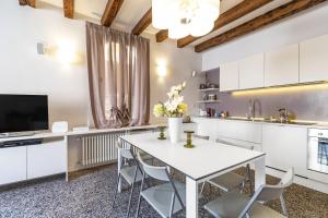a kitchen with white cabinets and a white table and chairs at CA FOSCA HOME - Campo Santa Fosca in Venice
