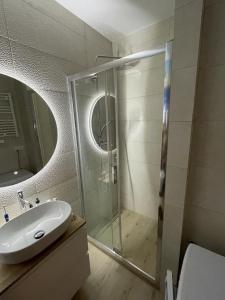 a bathroom with a glass shower and a sink at Apartament Jantar Osiedle Bursztynowe Jantar PROMOCJA in Jantar