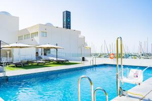 a pool with chairs and umbrellas next to a building at Moon Hotel & SPA. in Aguadulce