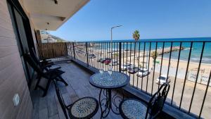 a balcony with a table and chairs and a view of the beach at PORT CITY HAIFA - Beach front luxury apartment - MAMAK in Haifa