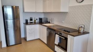 a kitchen with white cabinets and a stainless steel refrigerator at PORT CITY HAIFA - Beach front luxury apartment - MAMAK in Haifa