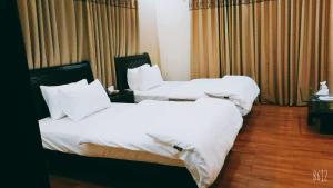 two beds in a hotel room with white sheets at The Elet Business Hotel in Karachi