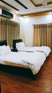 two beds in a hotel room with curtains at The Elet Business Hotel in Karachi