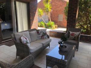 a patio with wicker chairs and a couch and a table at Eliora in Randfontein