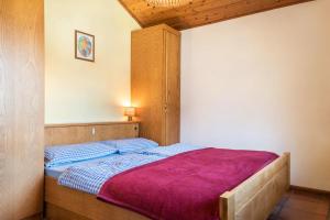 a bedroom with a bed with a purple blanket at Pension Sonia App 104 in Funes