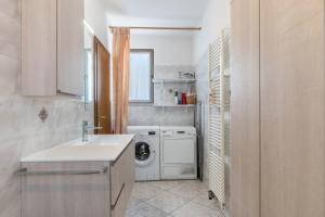 uma cozinha com uma máquina de lavar roupa e um lavatório em La Coccola di Giovanni em Levico Terme
