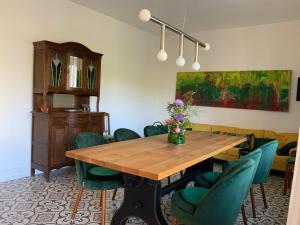 a dining room with a wooden table and green chairs at Ferienhaus Mosel 2.0 in Bremm