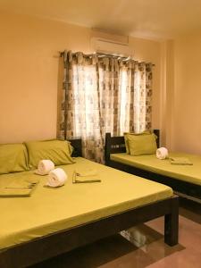 dwa łóżka z kapeluszami w pokoju w obiekcie E.I. SUITES w mieście Siquijor
