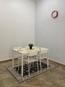 a white table with chairs and a clock on a wall at Homestay Ummi D'Pauh in Kota Bharu