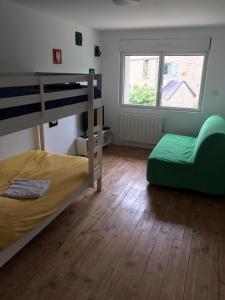 a bedroom with two bunk beds and a green chair at Gîte Le Coq Au Vert en Suisse Normande in Hamars