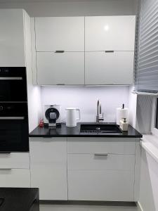 una cocina blanca con armarios blancos y fregadero en A modern apartment for 2 people, en Cracovia