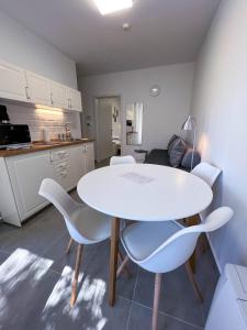 a kitchen with a white table and white chairs at Lujza Apartman in Fonyód