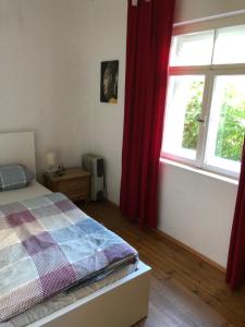 Wohnung mit Charme في ميونخ: غرفة نوم بسرير ونافذة ذات ستائر حمراء