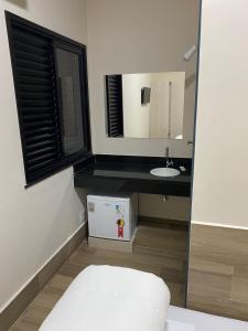 La petite salle de bains est pourvue d'un lavabo et d'un miroir. dans l'établissement AVENIDA HOTEL DE RESENDE, à Resende