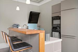 a kitchen with a counter with stools and a sink at The Sleek Gem of Central Wakefield - Parking in Wakefield
