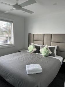 Lakeview House LILAC في Chittaway Point: غرفة نوم بسرير كبير عليها منشفة بيضاء