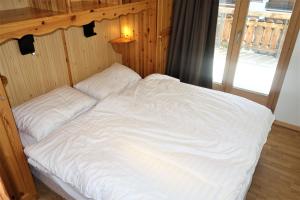 un grande letto bianco in una stanza con una finestra di Pracondu OUTDOOR & FUN appartement 1 chambre avec balcon by Alpvision Résidences a Nendaz