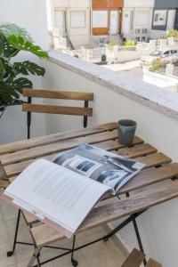 ein offenes Buch auf einem Holztisch auf einem Balkon in der Unterkunft Casa Boma Lisboa - Shining & Spacious Apartments With Balcony - Alvalade I in Lissabon