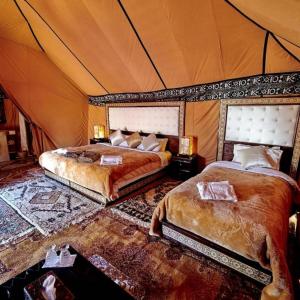 a bedroom with two beds in a tent at Desert Lover's Luxury Camp in Merzouga