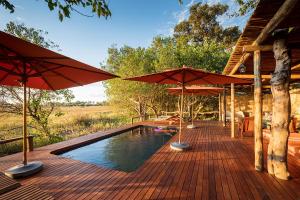 a deck with umbrellas and a swimming pool at Amber River Camp in Okavango Delta